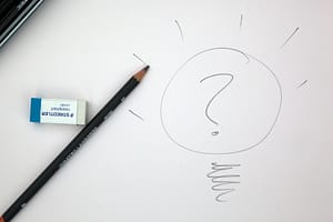 a pen and a rubber on a piece of white paper and a question mark